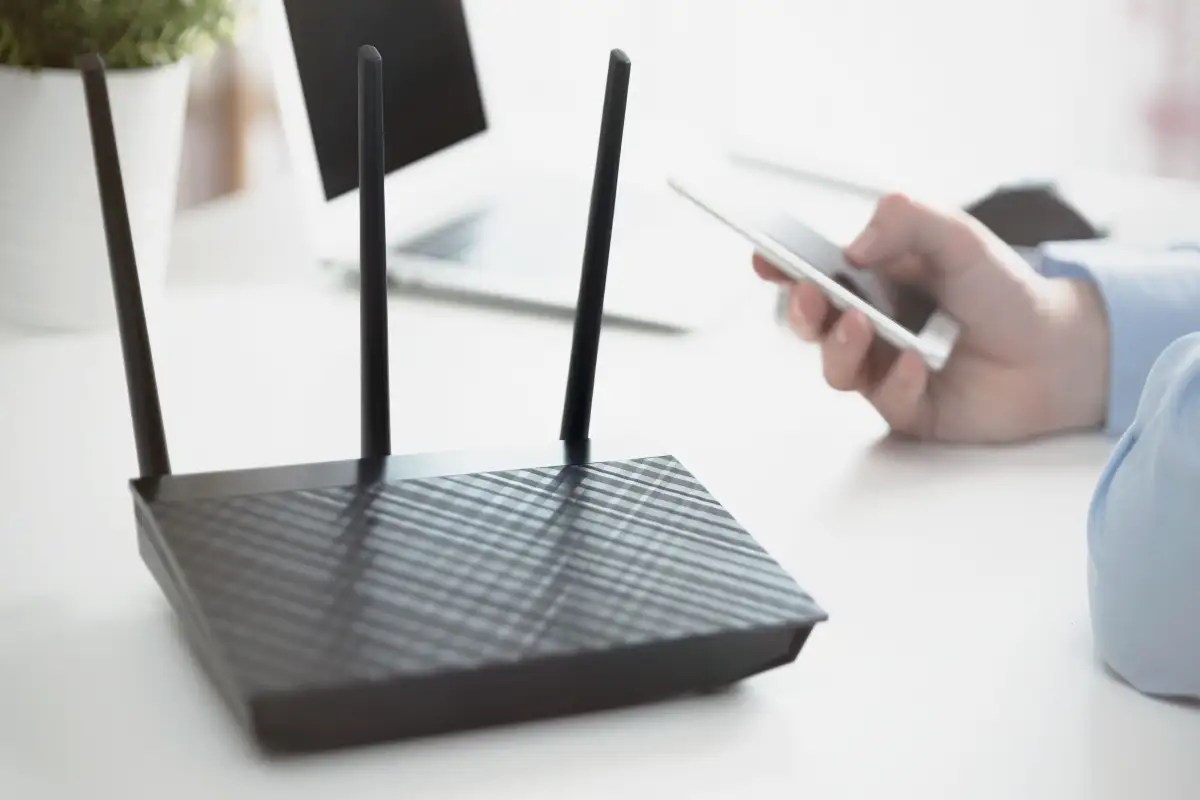 An image of a Wi-Fi router on a table with a mobile phone connected to said router